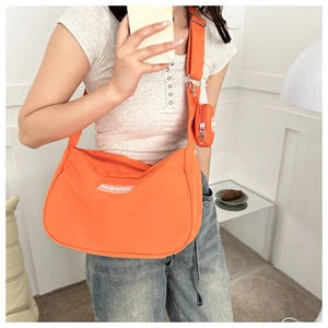 Dettaglio borsa a tracolla in nylon arancione con piccolo portamonete e etichetta Fashion
