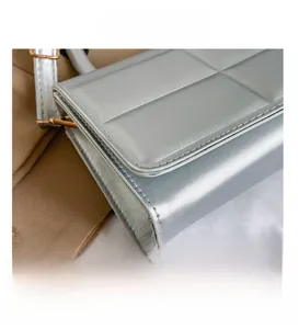 Detail presentation of silver grey quilted handbag with golden D-ring hardware and stitching
