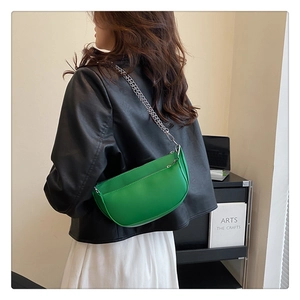 Detail of bright green half-moon bag with silver chain strap and zipper compartment