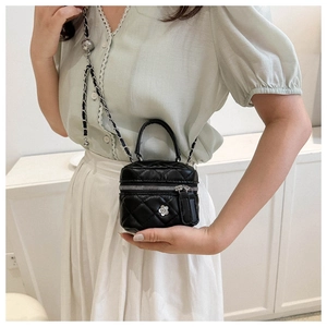 Mini black quilted leather crossbody bag featuring a chain strap and floral charm detail