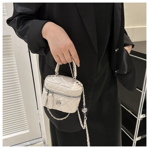 Detail of quilted white mini bucket bag with silver camellia charm and chain strap