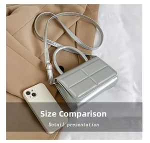 Detailed size comparison of the silver geometric handbag with a smartphone reference