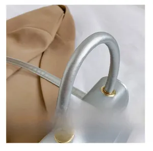 Detail presentation of silver handbag handle with golden eyelets and fine stitching