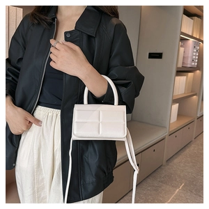 Detail of off-white crossbody bag with square embossed pattern and top handle