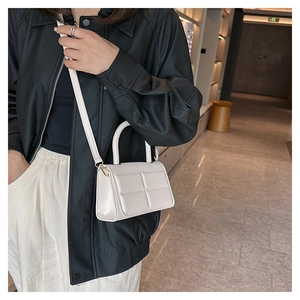 Quilted crossbody bag in cream white faux leather worn by a model in a stylish outfit