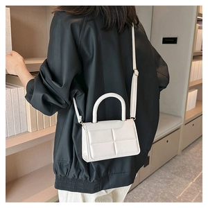 Rear view of model wearing a white quilted crossbody bag with top handle and strap