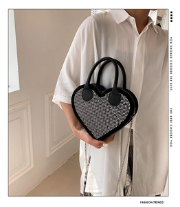 Detail of a black heart-shaped handbag with sparkling rhinestones and silver chain strap