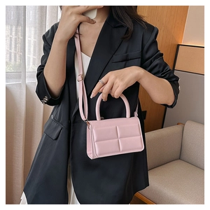 Detail of pink quilted square texture on crossbody bag with top handle and leather strap
