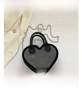 Detail of heart-shaped handbag with silver rivets and metallic chain on white fabric