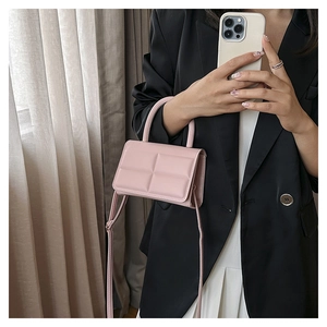 Close-up of pink quilted mini crossbody bag with top handle shown in a mirror selfie