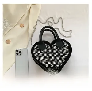 Close-up of heart-shaped handbag with silver studs and elegant metal chain strap