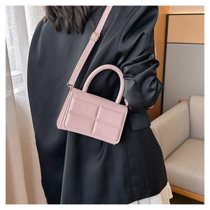 Detail of light pink quilted square handbag showing round handle and adjustable strap
