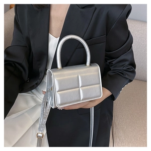 Silver square crossbody bag with textured metallic leather finish worn with a black blazer