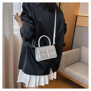 Detailed view of silver quilted crossbody bag with circular handle on a model