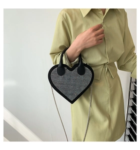 Detail of heart-shaped handbag with rhinestones and silver chain strap on model