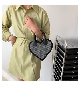 Detail of heart-shaped handbag with sparkling rhinestones and metal chain strap