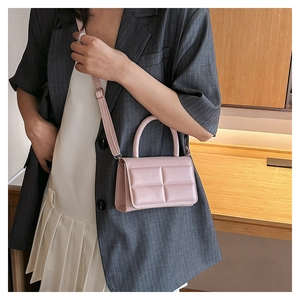 Light pink quilted crossbody bag styled with a gray suit and white pleated skirt