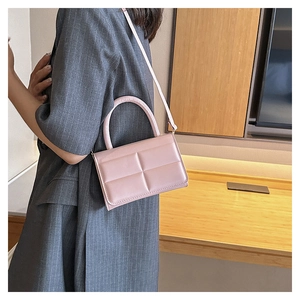 Detailed view of pink quilted handbag with round handle and matching crossbody strap