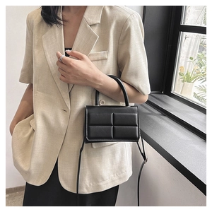 Model wearing a black quilted crossbody bag with a sleek handle and flap closure