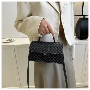 Detail van zwarte crossbodytas met grijze geometrische patronen en witte stiksels