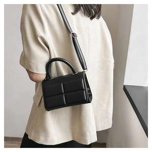 Detail of black quilted square flap bag with adjustable strap and top handle