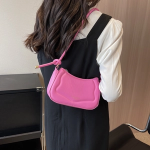 Rosa plissierte Schultertasche aus Leder mit Knotendetail, am Modell in minimalistischer Umgebung