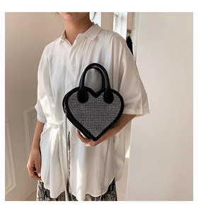 Macro detail of heart-shaped handbag featuring sparkling rhinestones and silver chain