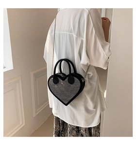 Model wearing a black heart-shaped handbag with silver rhinestones and metal chain