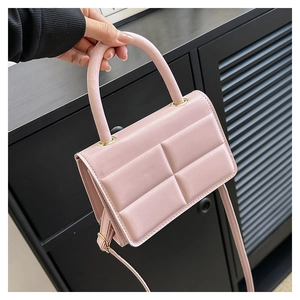 Detail of light pink quilted shoulder bag with top handle and gold hardware accents