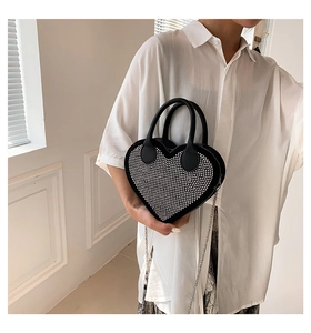 Detail of heart-shaped handbag featuring shimmering crystals and metal chain strap