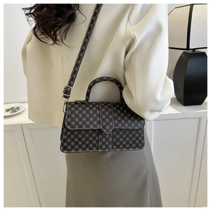 Detail achteraanzicht van een vintage crossbody tas op een model in een minimalistische kamer
