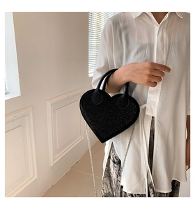 Close-up of black heart-shaped handbag with shimmering rhinestones and silver chain strap
