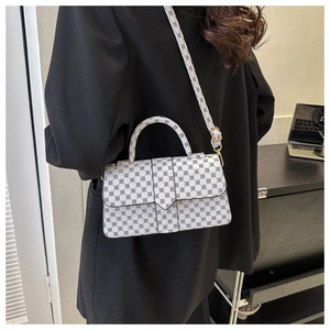 Detailopname van een witte geometrische crossbodytas gedragen op een zwarte blazer