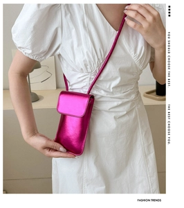 Détail du sac de téléphone rose rouge métallisé avec bandoulière sur robe blanche