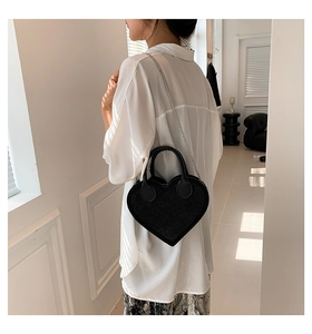 Detail of black heart-shaped handbag with sparkling finish and silver chain strap