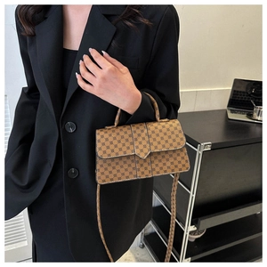 Detailweergave van een bruine crossbodytas met geometrisch patroon en handvat