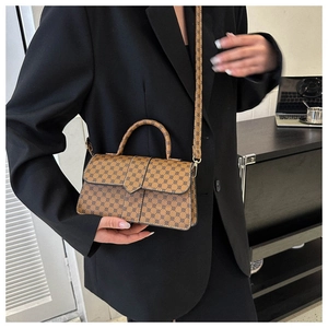 Bruine monogram crossbodytas gedragen met een zwarte blazer in een moderne kantooromgeving