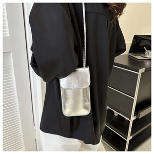 Detail einer glänzenden silbernen Handytasche mit eleganter Umhängetasche in Spiegeloptik