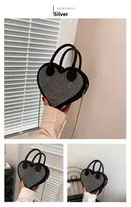Detail of a heart-shaped bag featuring silver rhinestones and metal chain strap