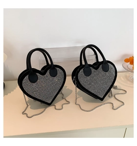 Detail of black heart-shaped handbag featuring full crystal studs and silver chain strap