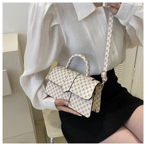 Detail van een witte crossbodytas met patroon, gouden hardware en schouderriem
