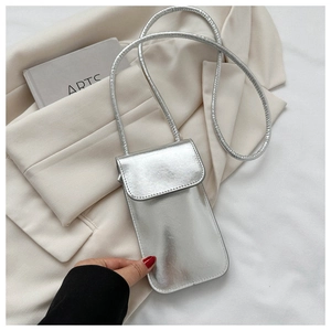 Detail einer silbernen Metallic-Handytasche mit Schultergurt auf einem Blazer