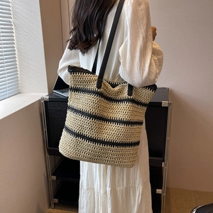 Striped straw tote bag with black faux leather handles for summer beach vacations