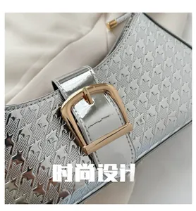 Gros plan d'un sac argenté en cuir verni pied-de-poule avec fermoir doré brillant