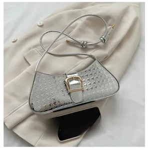 Détail du sac baguette argenté avec motif étoiles et boucle métallique carrée dorée