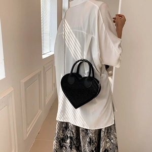 Sparkling black heart-shaped handbag with silver chain strap shown in a lifestyle setting
