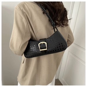 Détail du sac baguette en cuir verni noir avec texture pied-de-poule et boucle dorée