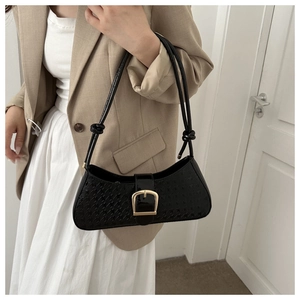 Détail du sac baguette pied-de-poule noir avec boucle fer à cheval dorée et nœuds stylés