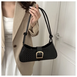 Détail du sac en cuir verni noir avec boucle dorée et bandoulière à nœuds élégants