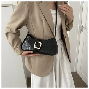 Détail du sac bandoulière en cuir verni noir avec motif pied-de-poule et boucle dorée
